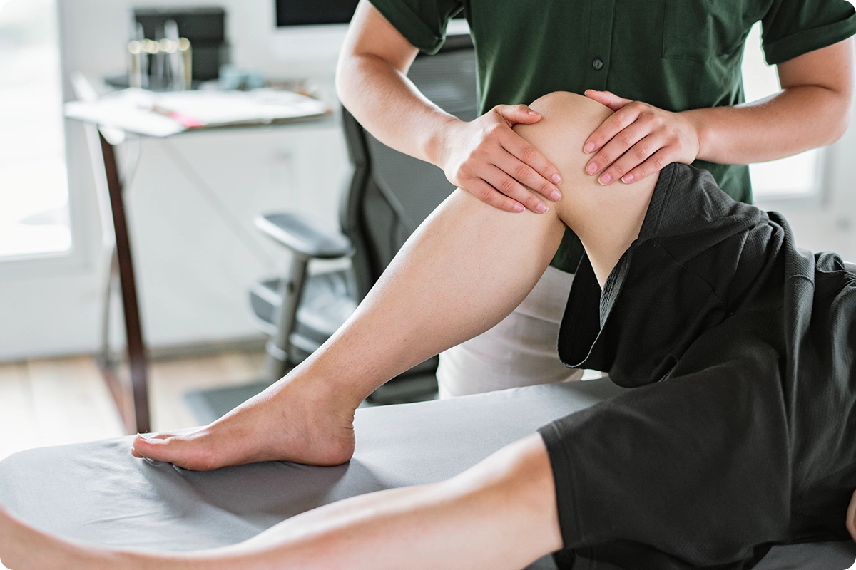 Physical therapist massages patient's knee.