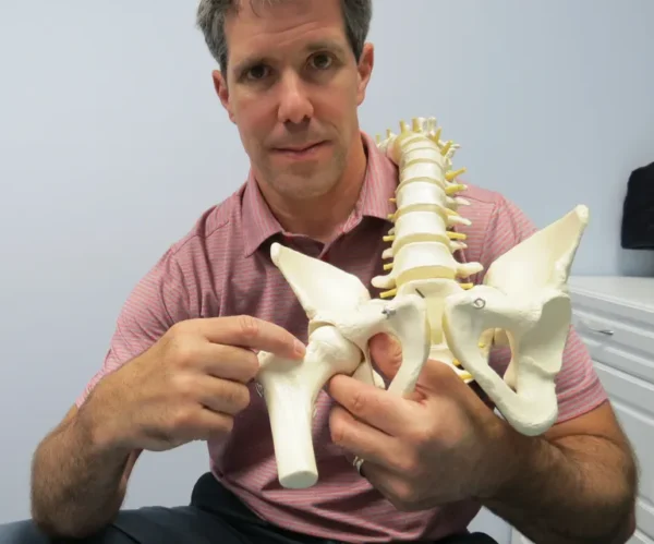 A man holding up a model of the human spine.